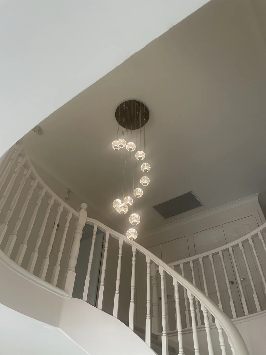 Cascading multi-pendant feature light installed over a curved stairwell in a Carindale home by Moritz Electrical
